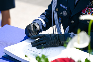 kolorowe zdjęcie dłoni policjanta, podczas podpisywania dokumentu
