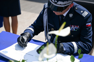 kolorowe zdjęcie przedstawiające Generała Policji składającego podpis na dokumencie