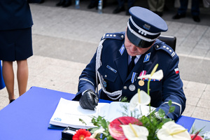 kolorowe zdjęcie Oficera Policji składającego podpis na dokumencie