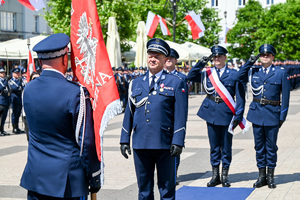 kolorowe zdjęcie przedstawiające policjantów oddających honor do sztandaru