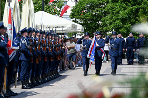 kolorowe zdjęcie policjantów maszerujących ze sztandarem, widoczna Kompania Honorowa Policji z karabinami