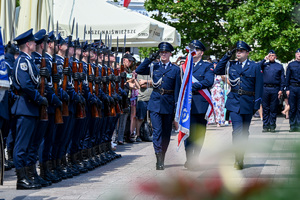 kolorowe zdjęcie policjantów maszerujących ze sztandarem, widoczna Kompania Honorowa Policji z karabinami