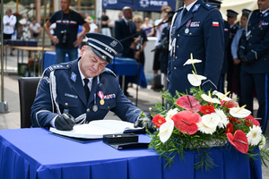 kolorowe zdjęcie przedstawiające Oficera Policji składającego podpis na dokumencie