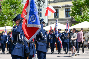 kolorowe zdjęcie przedstawiające policjantów trzymających sztandary, policjanci oddają honor