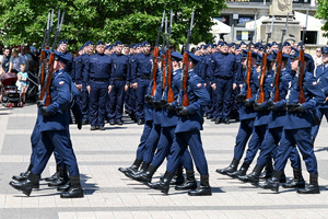 kolorowe zdjęcie maszerujących policjantów kompani honorowej, w tle policjanci stojący na baczność