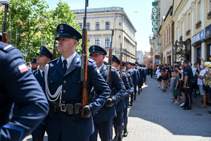 kolorowe zdjęcie policjantów kompani honorowej maszerujących ulicami miasta