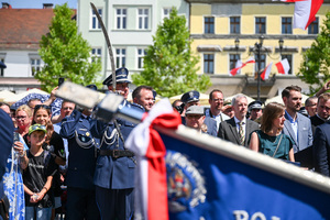 kolorowe zdjęcie głowicy sztandaru, w tle policjant Kompani Honorowej unoszący szablę