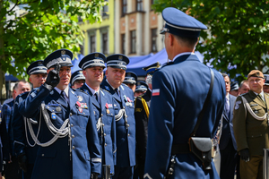 Kolorowe zdjęcie przedstawiające Generała Policji oddającego honor, stojącego wraz z gośćmi honorowymi obchodów Święta Policji