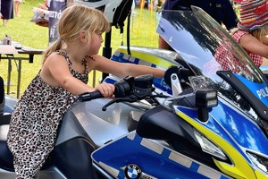 kolorowe zdjęcie dziewczynki siedzącej na motocyklu policyjnym