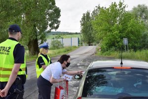 policjantka i pracownicy PKP podczas wręczania kierowcy ulotki w tle przejazd kolejowy