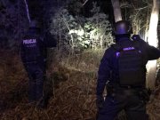 dwaj policjanci w hełmach patrolują granice nocą świecąc latarkami