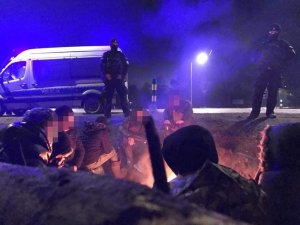 imigranci ogrzewają się przy ognisku