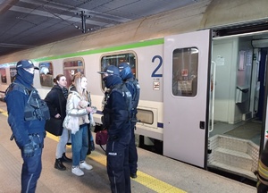 trzech policjantów rozmawia z kobietami na peronie dworca