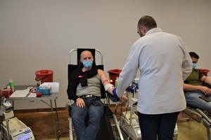 mężczyzna oddaje krew, przy nim pracownik RCKiK