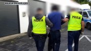 policjanci prowadzą zatrzymanego mężczyznę do radiowozu