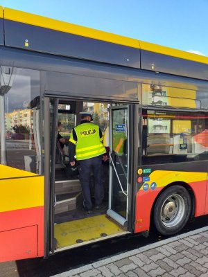 Umundurowany policjant w autobusie komunikacji miejskiej.