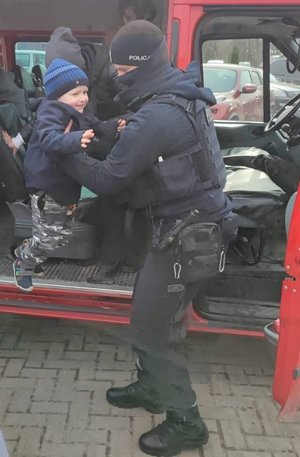 policjant wynosi z busa małego chłopca
