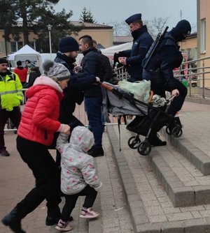 policjanci pomagają wnosić wózki dziecięce po schodach