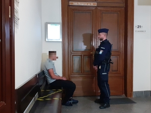 zatrzymany męzczyzna obok którego znajduje sie umundurowany policjant