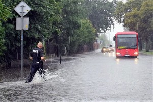 Zdjęcia przedstawiają policjanta przemieszczającego się po zalanej ulicy