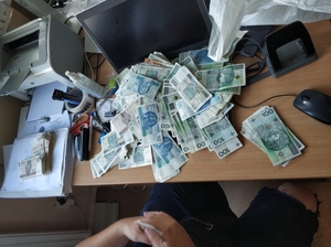 Na biurku obok komputera leży stos banknotów