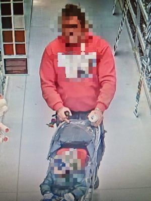 Na zdjęciu widoczny jest mężczyzna w czerwonej bluzie prowadzący dziecięcy wózek. Obraz częściowo zamazany.