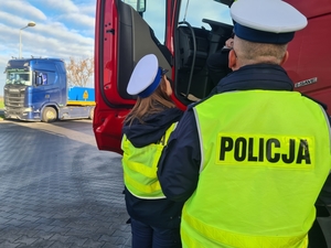 policjanci w mundurach i kamizelkach stoją przy samochodzie ciężarowym