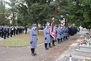 policjanci w mundurach galowych stoją przy sztandarze