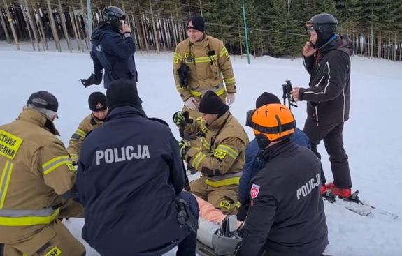 policjanci pomagają poszkodowanemu na stoku