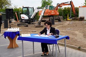 Na zdjęciu Marszałek Sejmu RP Pani Elżbieta Witek podpisująca akt erekcyjny w tle plac budowy i maszyny budowlane.
