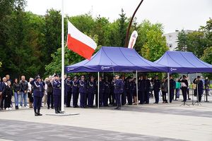 Zaproszeni goście, kadra kierownicza dolnośląskiej policji i oficjele oddają honory fladze Polski powiewającej na maszcie.