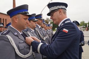 Komendant Wojewódzki Policji we Wrocławiu przypina medal policjantowi.