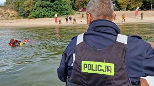 Policjant podczas ćwiczeń z łódki obserwuje jak żołnierze ratują tonącego człowieka