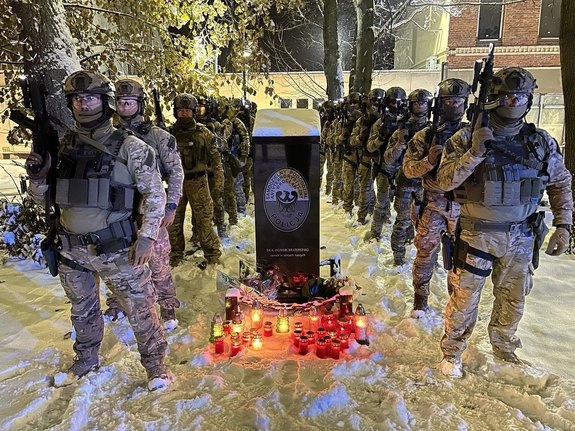 policyjni kontrterroryści stojący po obu stronach czarnego pomnika