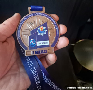 mężczyzna trzyma w ręce medal za zdobycie 3 miejsca