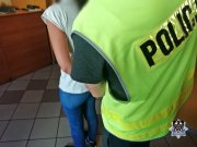 Na zdjęciu policjant prowadzi kobietę zatrzymaną za oszustwa na policjanta