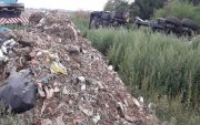 Na zdjęciu na pierwszym planie nielegalnie  wysypane odpady na polu, w tle ciągnik siodłowy wraz z naczepą, który osunął się do rowu.