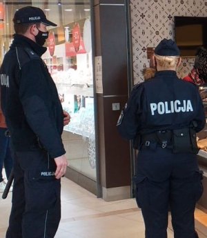 Na zdjęciu policjant i policjantka kontrolujący obiekty handlowe.