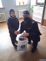 Policjant w mundurze podaje prezent małemu chłopcu