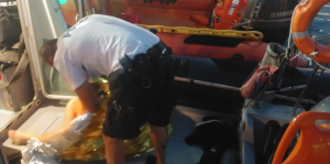 policjant trzyma wyciągniętego z wody mężczyną