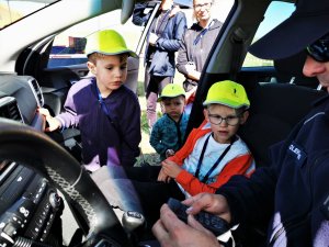 oglądające policyjny radiowóz dzieci w odblaskowych czapeczkach