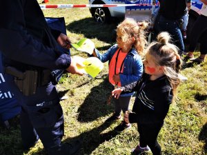 policjant daje czapeczki dwóm dziewczynkom