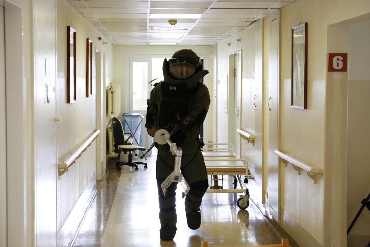 Policjant z Samodzielnego Pododdziału Kontrterrorystycznego ubrany w strój ochronny w tle korytarz szpitala.
