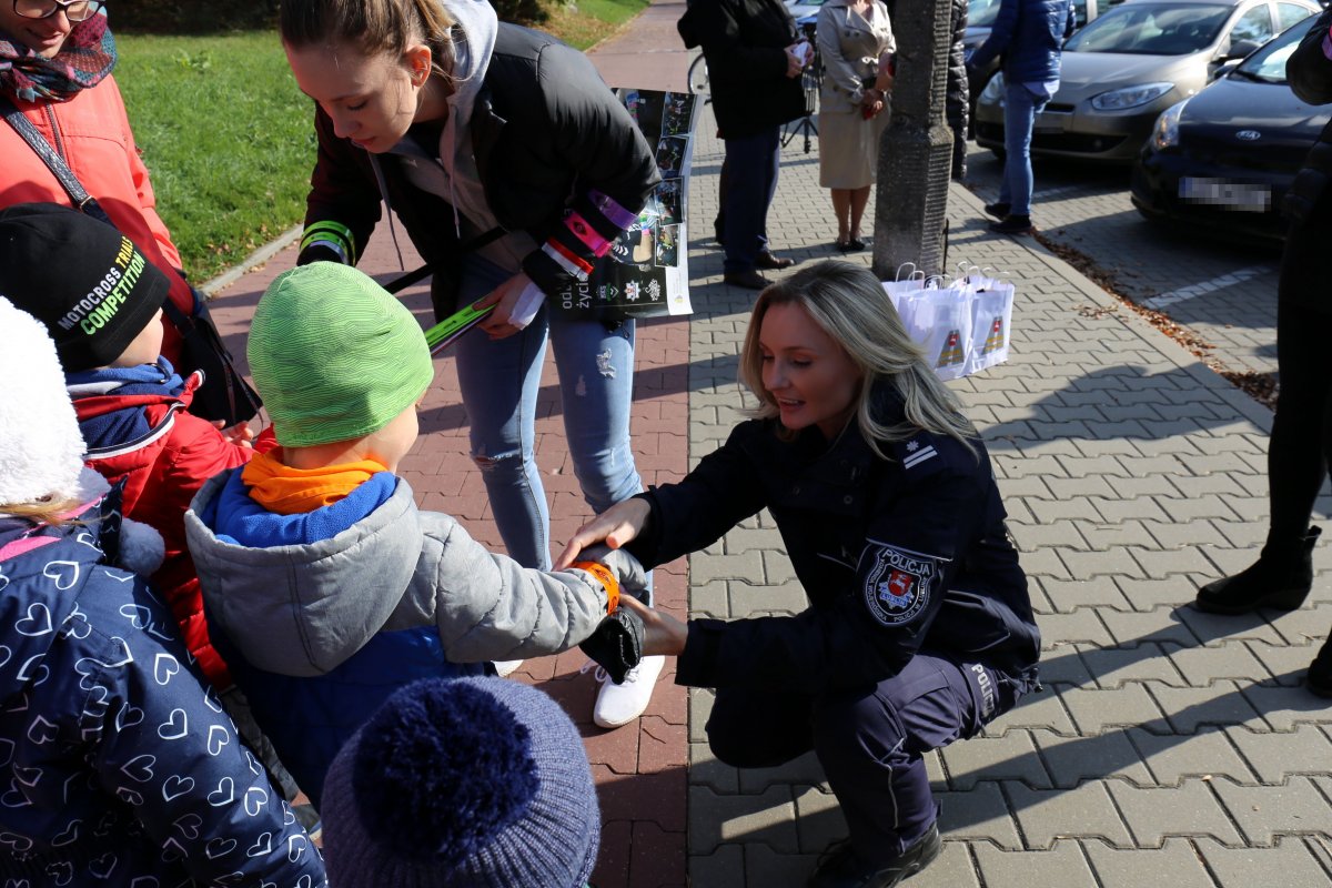policjantka i zawodniczka rozdają dzieciom odblaski