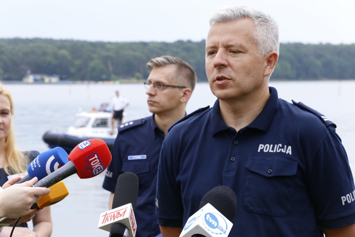 Komendant Wojewódzki Policji w Lublinie na tle zalewu zemborzyckiego udziela wywiadu dziennikarzom.