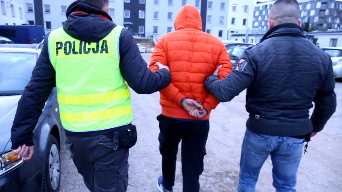 Policjanci prowadzą zatrzymanego mężczyznę do budynku Komendy Miejskiej Policjie w Lublinie.