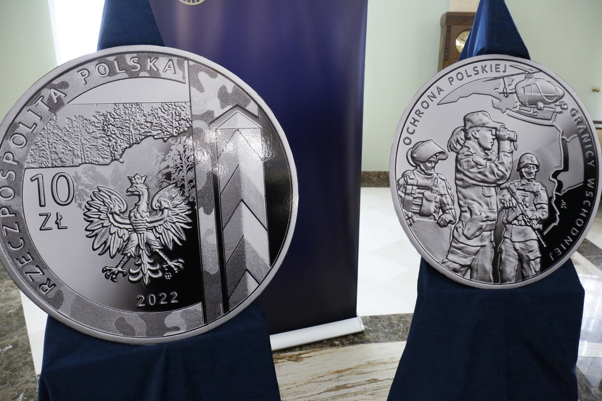 Zdjęcie przedstawia monety okolicznościowe z obu stron na których widać służby na granicy Polski.