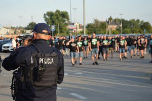 policjant przed stadionem i kibice