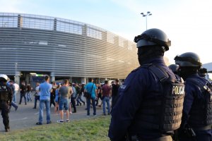 policjanci przed stadionem i kibice w drodze na mecz