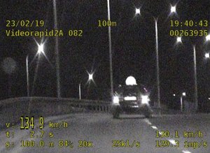 Zdjęcie przedstawia nagranie z radiowozu. Na nagraniu widać jak kierowca volkswagena przekracza prędkość na ulicy Andersa jadąc lewym pasem ruchu. Na prawym pasie ruchu widać wyprzedzane pojazdy.